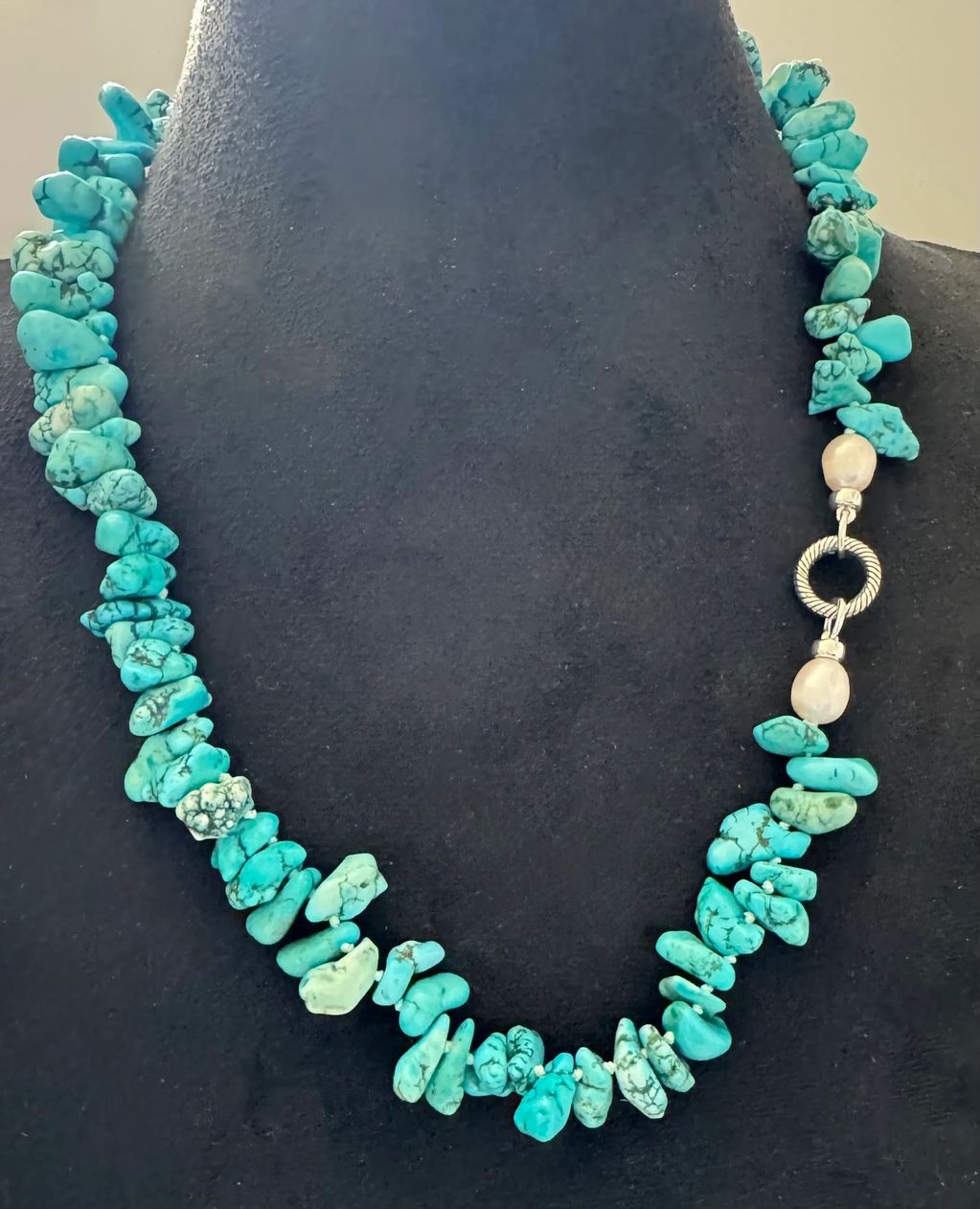 Turquoise stone necklace with silver and pearl clasp.