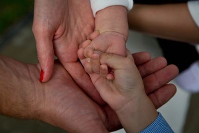 Multiple hands of different ages joined together symbolizing family unity.