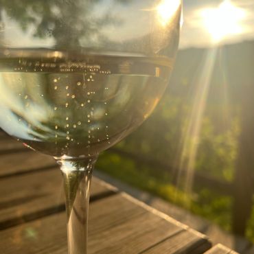 A glass of sparkling drink with sunlight shining through it on a wooden table.