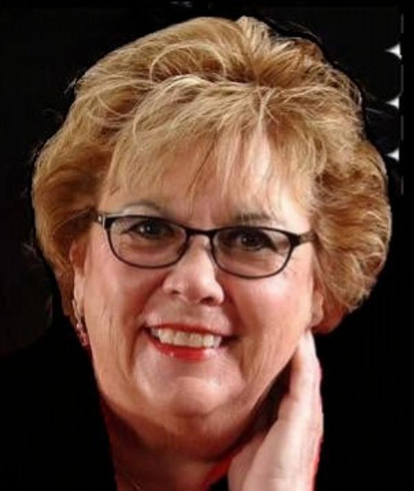 Smiling woman with glasses and short blonde hair.