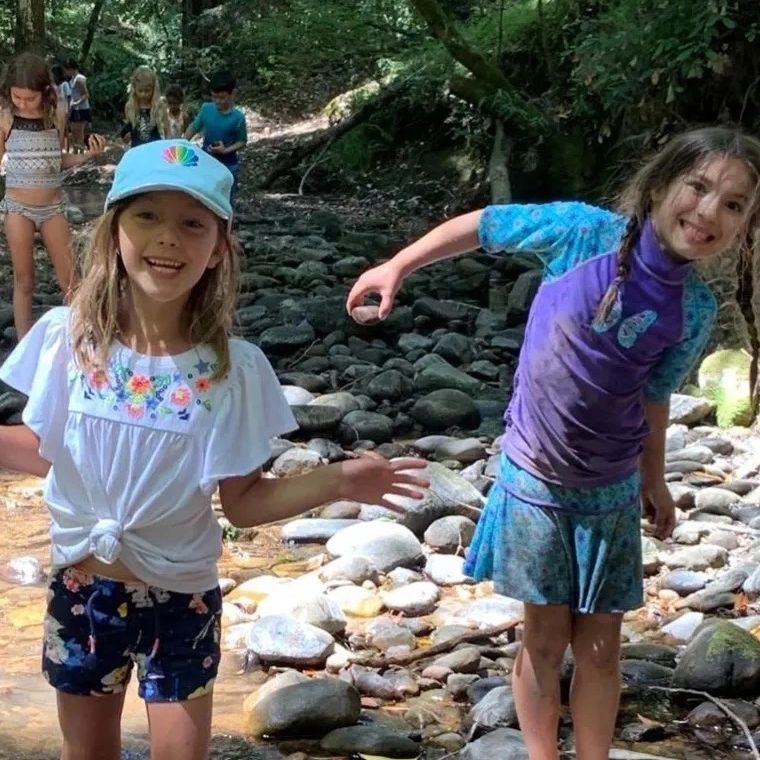 Two happy girls playing by a rocky creek.