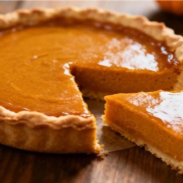 A pumpkin pie with a slice being lifted out.