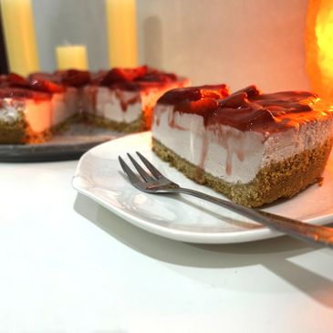 Slice of strawberry cheesecake with a fork on a white plate.
