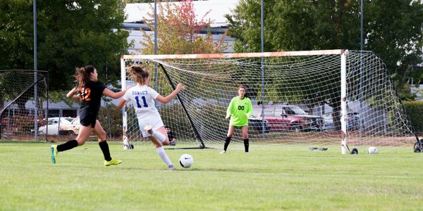 high school soccer girl scores a goal