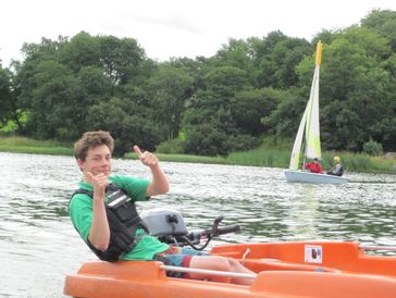 A happy instructor giving thumbs up on a commando power boat with a dinghy in the background.