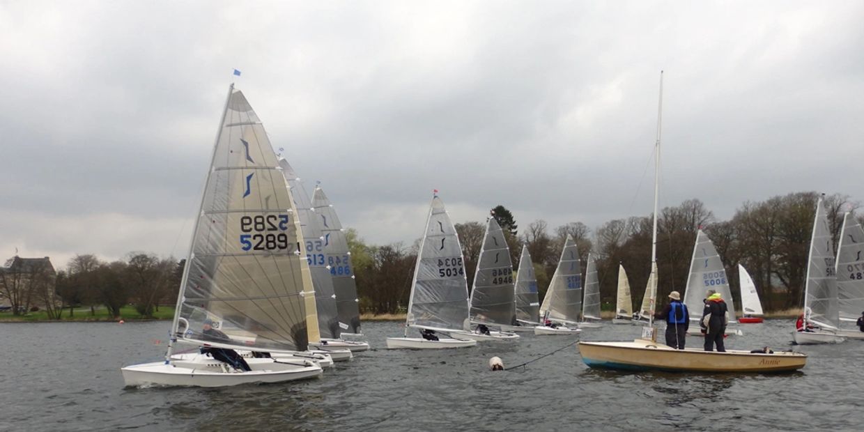 Solos crossing the start line marked by the moored Laser 16 "Annie" at the 2017 Traveller.