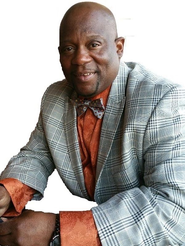 Man in a checkered blazer and orange shirt with a bow tie.