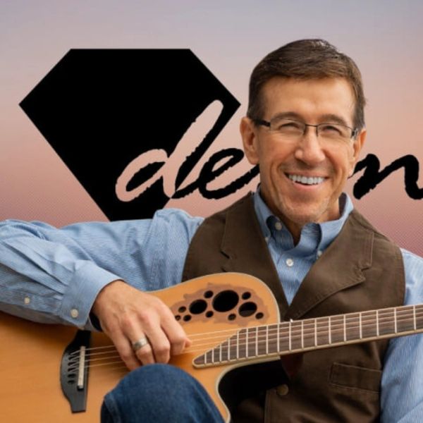 Man smiling while holding an acoustic guitar.