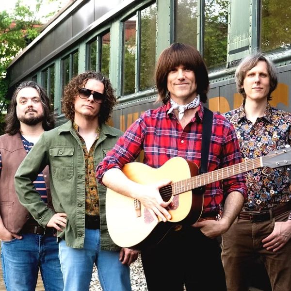 Group of four men, one with a guitar.