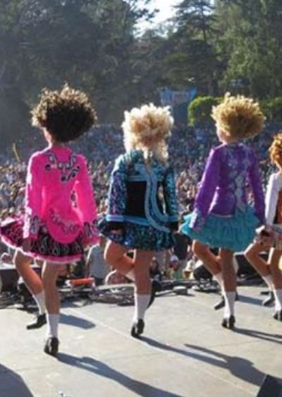 Young dancers in colorful costumes performing an Irish dance on stage.