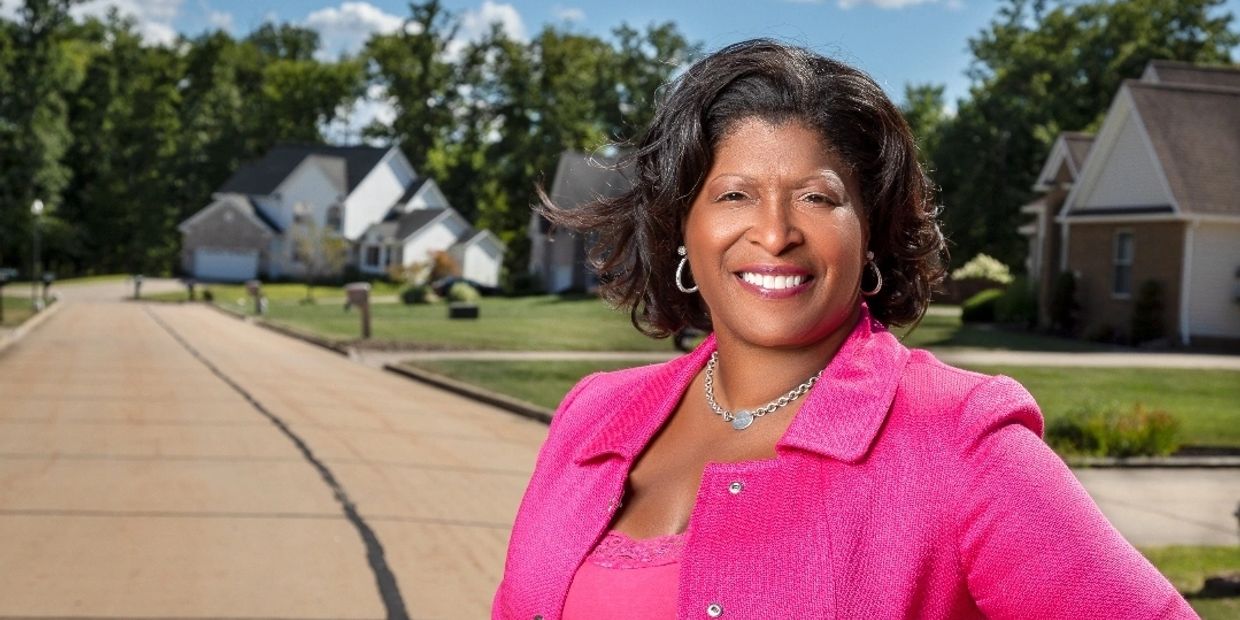 Woman smiling in a pink outfit on a suburban street.