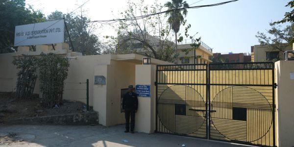 Entrance gate of a company with a security guard standing outside.