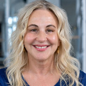 Smiling blonde woman with wavy hair.