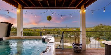 Beautiful view of the lake from the deck with a hot tub and string lights