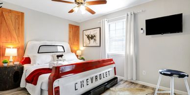 Bedroom decorated in Texas farmhouse style with a truck bed bed and longhorn art