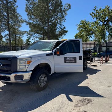 White service truck parked near a gated community entrance on a sunny day.