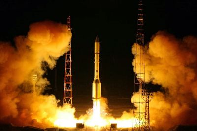 Rocket launching at night with bright flames and smoke.