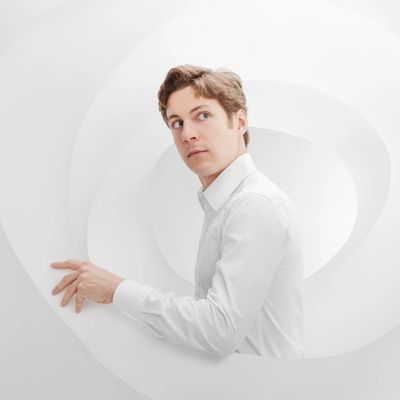 Man in white shirt in a white abstract spiral setting.