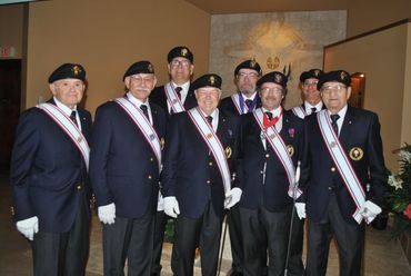 older men with suits and berets wearing sashes
