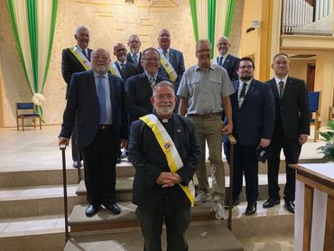 group of men with a priest standing on some steps