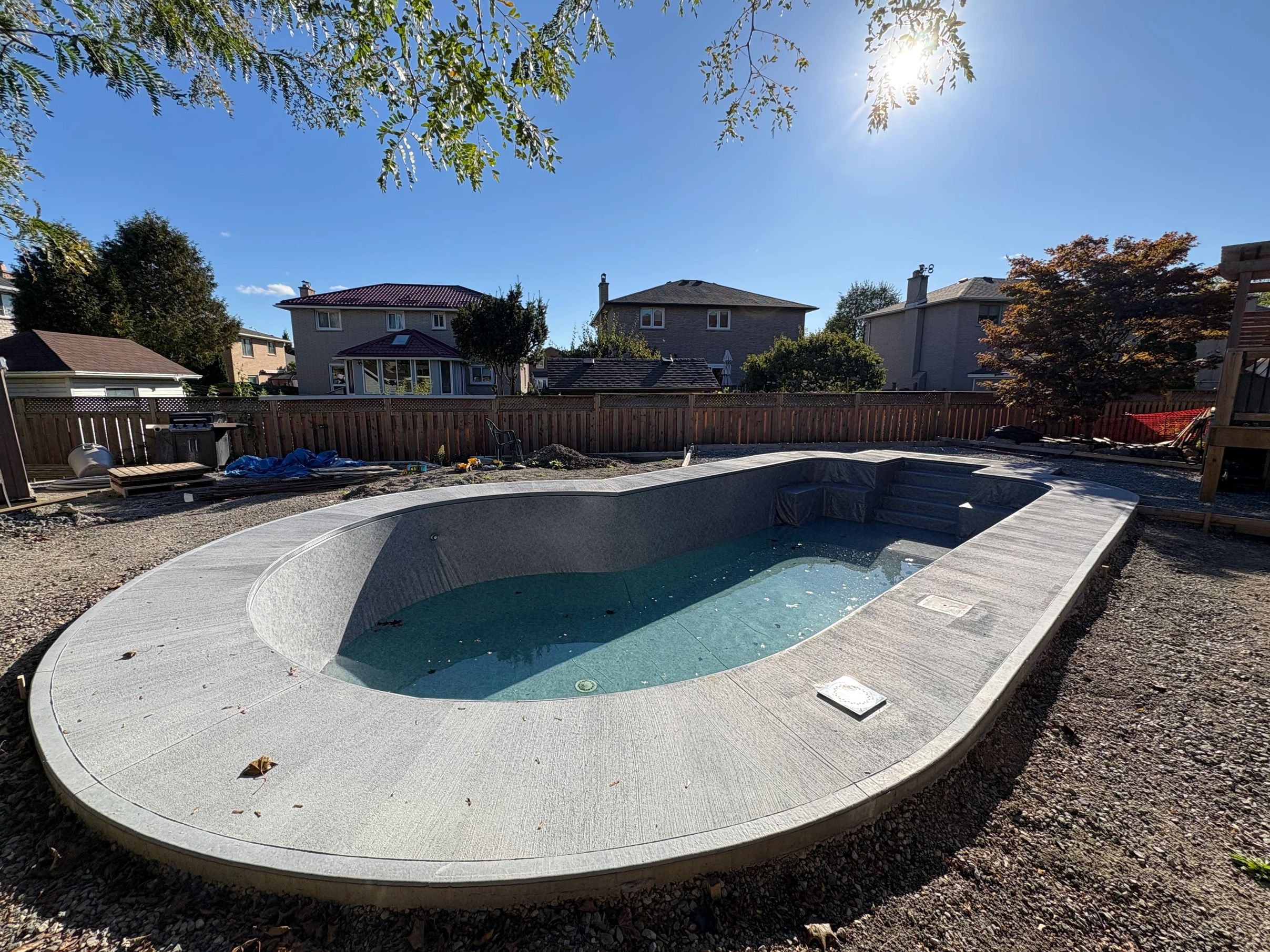 Newly constructed backyard pool with clear water on a sunny day.