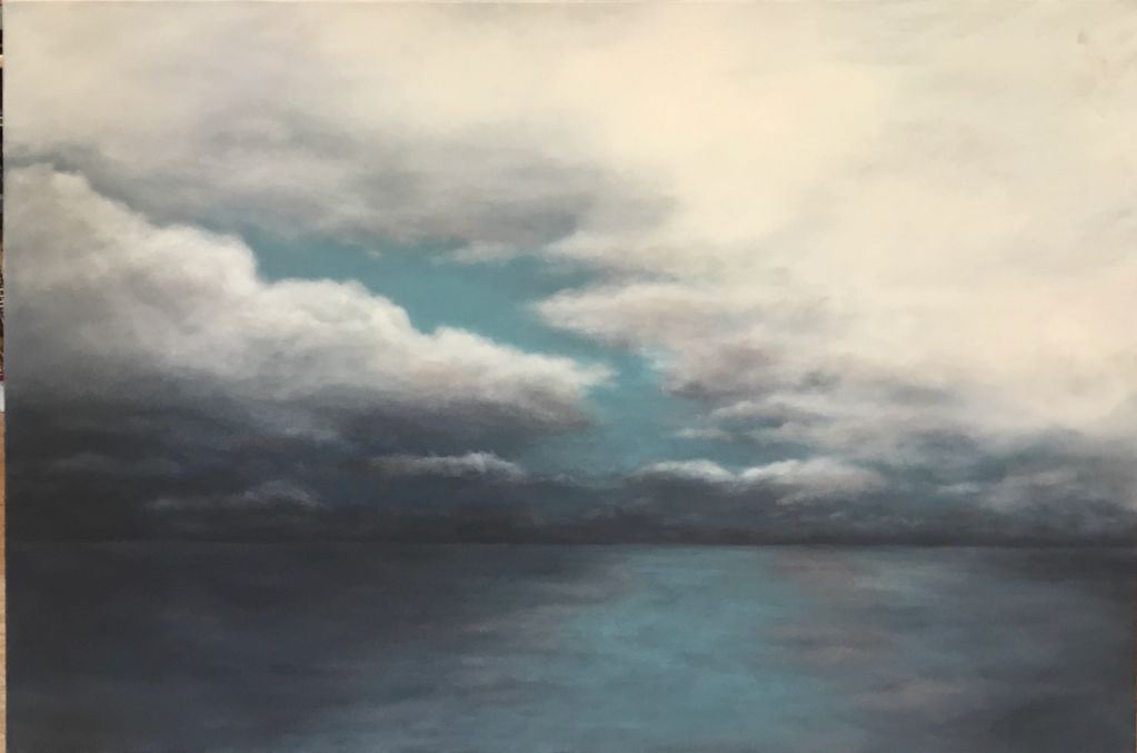A calm sea under a cloudy sky with a patch of blue.