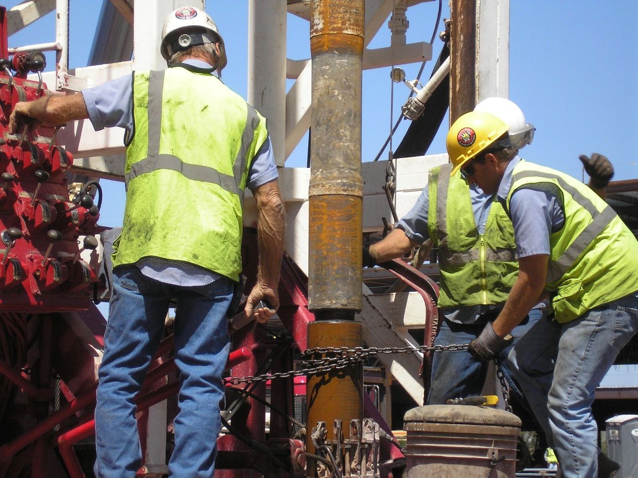 Workers operating heavy machinery on construction site.