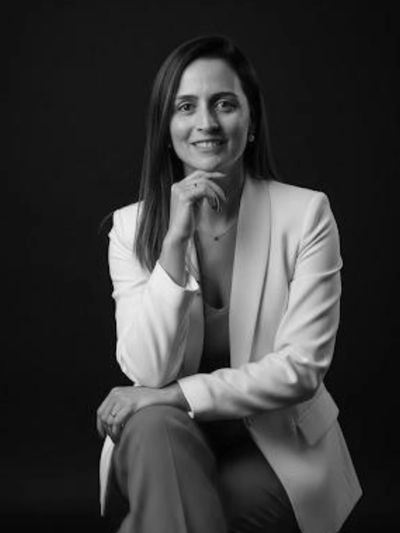 Professional woman in a white blazer posed against a black background.