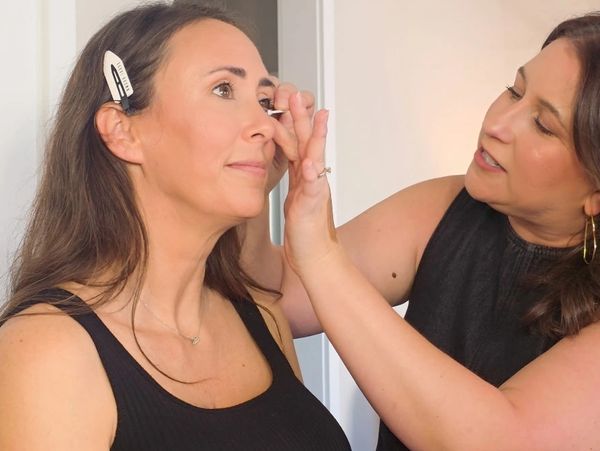 Woman applying makeup to another woman.
