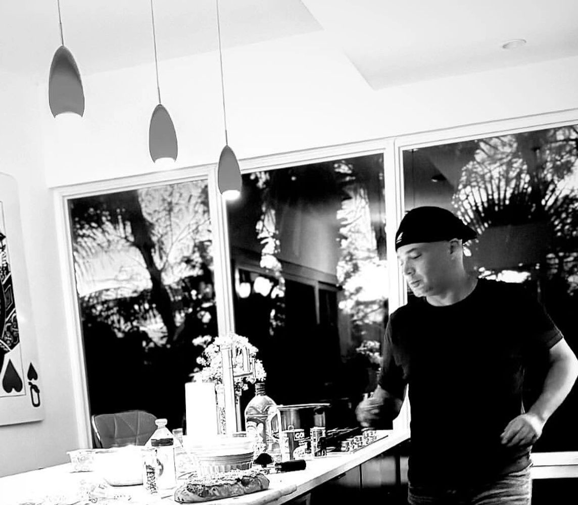 Man preparing food in a modern kitchen with a large Queen of Hearts card on the wall.