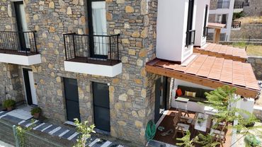 A modern stone and white exterior house with a cozy patio area.