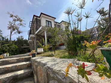 Beautiful house with stone steps surrounded by greenery and flowers.