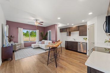 Open living room and kitchen with modern decor and purple accent wall.