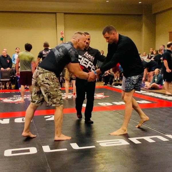Two martial artist shaking hands at a grappling tournament.