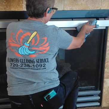 Person cleaning a fireplace wearing a Flowers Cleaning Service shirt.