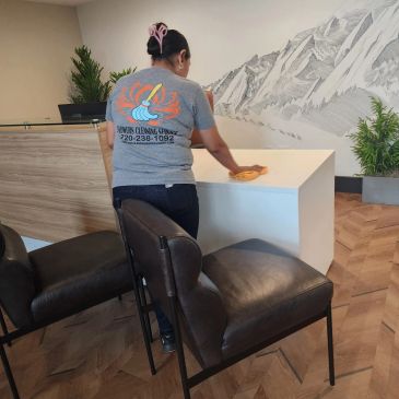 Person cleaning a white table in a modern interior space.