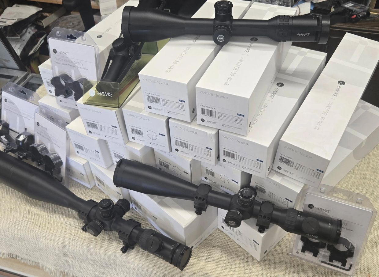 Hawke rifle scopes and mounts displayed on a table with packaging boxes.