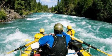Group of people rafting down a fast-flowing river surrounded by forest.