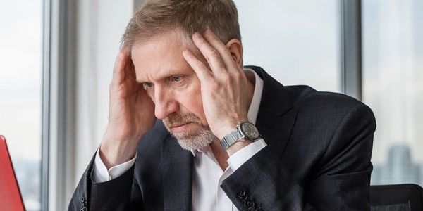 Man sat at desk feeling overwhelmed.