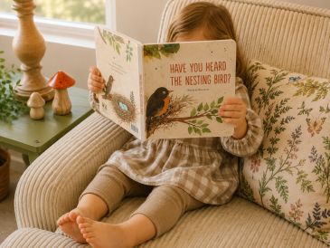 Child reading a bird-themed book indoors.