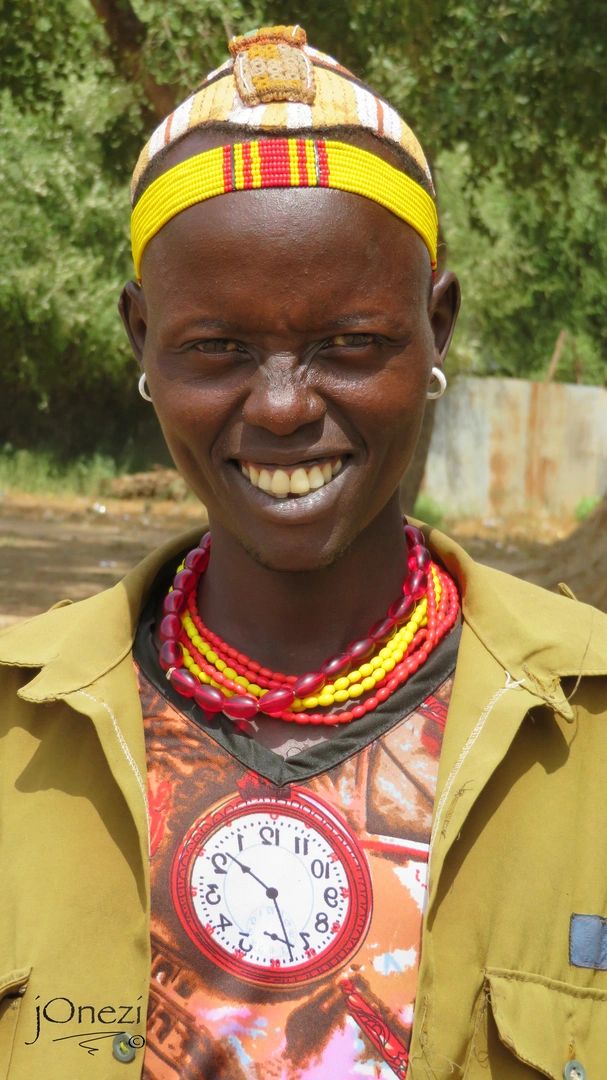 Portrait of a smiling 'Daasanech' tribal man wearing a colorful beaded necklace and traditional head