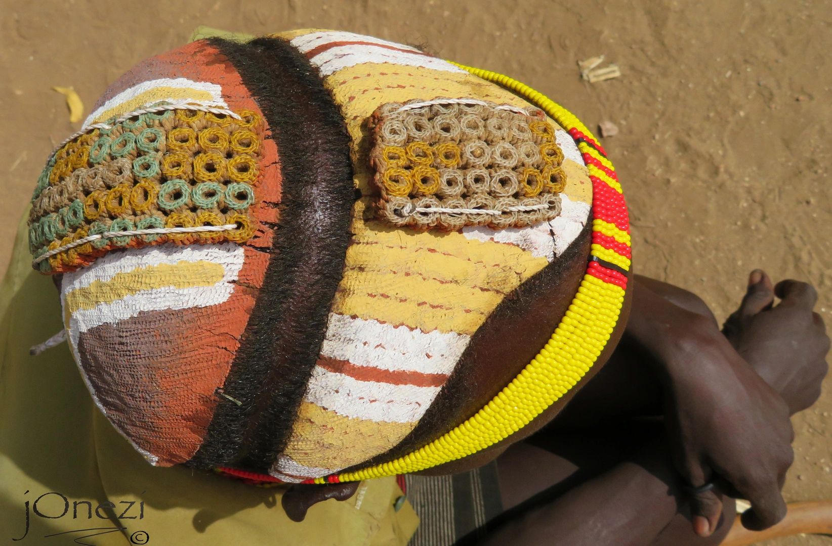 Intricately painted and beaded tribal hairstyle viewed from above.