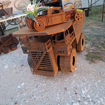 Metal sculptures of vehicles with a plant on top.