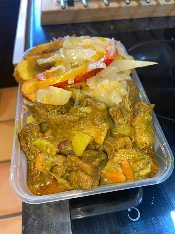 Curry goat, rice and peas, festival, and fried plantain.
