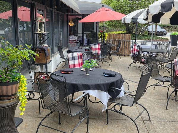 Outdoor dining area with black tablecloths and red umbrellas.