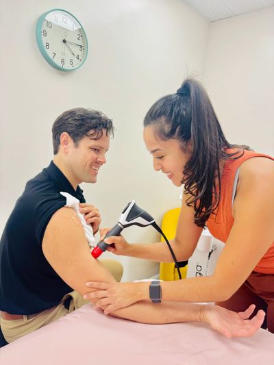 Dr. Nenny gliding radial shockwave over model's biceps. 