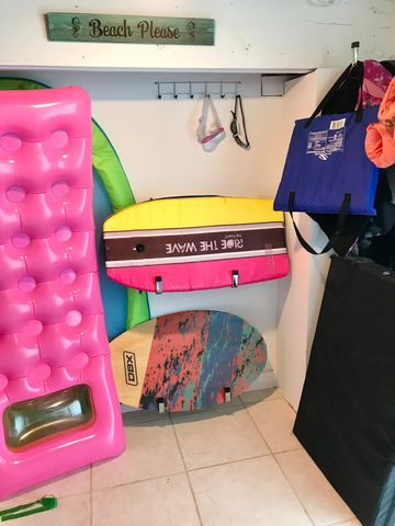 Beach closet with boogie boards, skimboards, goggles, life jackets, and cornhole game. 
