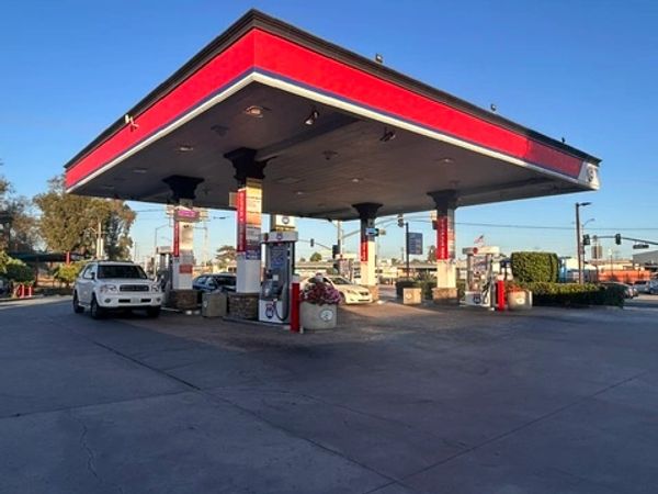 Gas station with cars refueling under a red canopy.