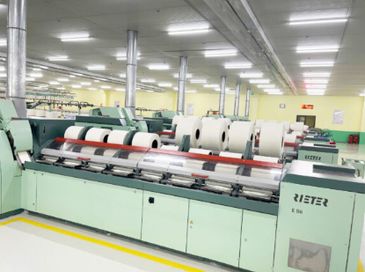 Industrial textile machinery producing yarn in a factory setting.