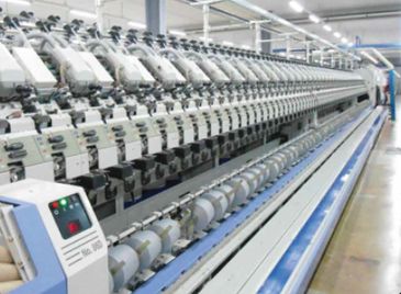 A long textile machine with multiple spindles in a factory.